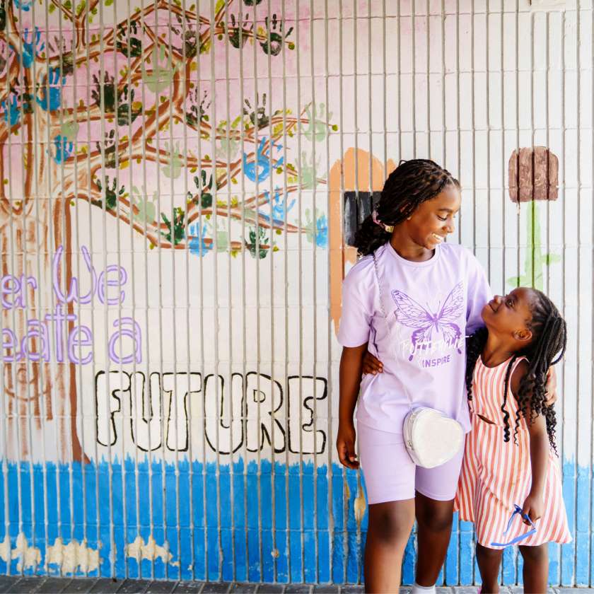 Girls standing next to a wall mural