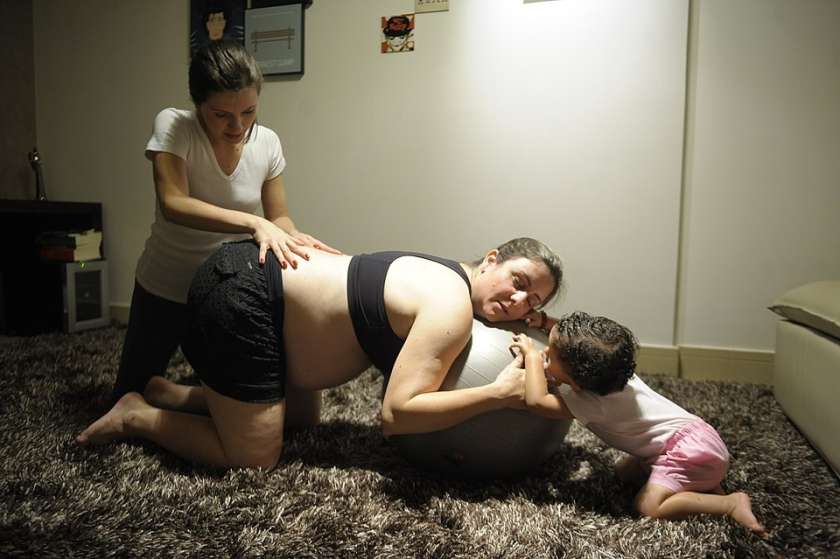 A doula (left) applying counter pressure to the pregnant person prior to labor.