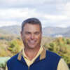 Dan Akers smiling in front of a mountain background