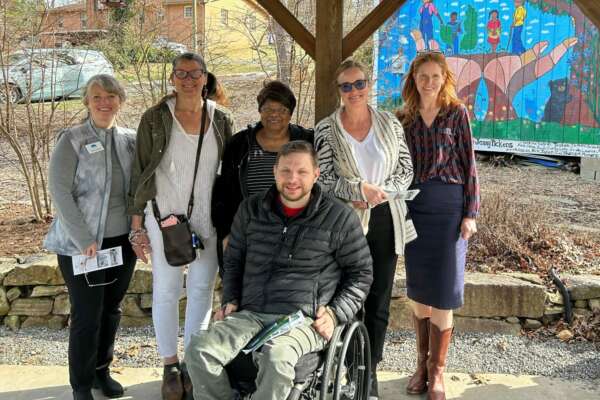 group stands in front of a mural in the Shiloh Community Center in Asheville NC
