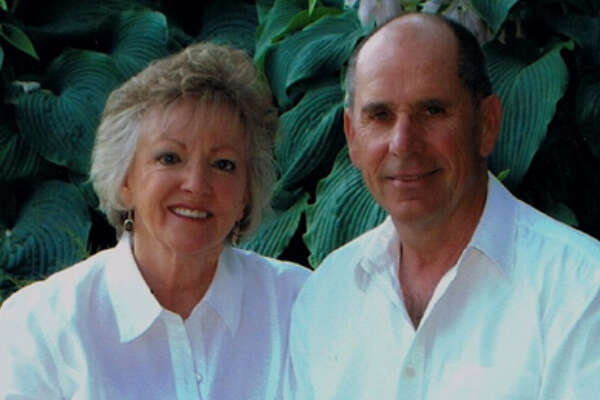 Howell Hammond and his wife posing in front of a leafy plant
